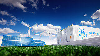 Auf einer Wiese sind Solar- und Windkraftanlagen sowie ein mit Wasserstoff befüllter Container zu sehen.