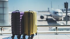 Suitcases in airport departure lounge, airplane in background, summer vacation concept, traveler suitcases in airport terminal waiting area, empty hall interior with large windows, focus on suitcases