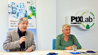 Corinna Enders und Harry Lehmann vor dem Logo des PtX Lab Lausitz