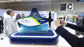 Model of an aircraft at an exhibition, surrounded by visitors.