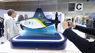 Modell eines Flugzeugs auf einer Messe, umringt von Besucher*innen