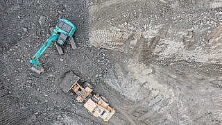 A top view shows an excavator and a truck at work.