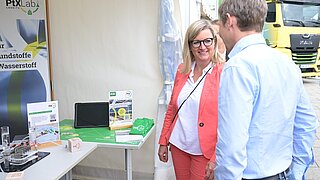 Brandenburgs Wirtschaftsministerin Martina Klement steht am Stand des PtX Lab Lausitz beim Brandenburger Energietag und spricht mit einem Vertreter des Labs.