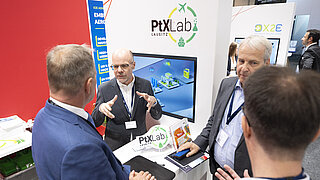Vier Personen diskutieren an einem Messestand.