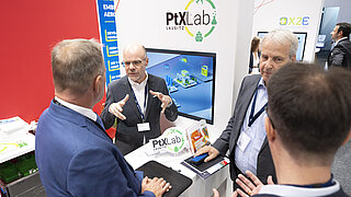 Four people in discussion at an exhibition booth.