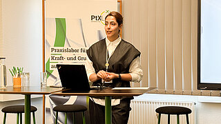 A person in the foreground. A banner and a whiteboard in the background.