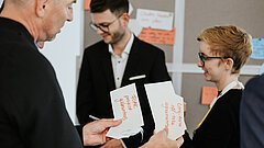 Eine Gruppe von drei Personen, die verschiedene Notizkarten bei einem betrachten