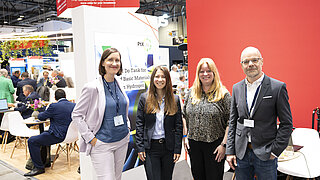 PtX Lab Lausitz Mitarbeiter stehen gemeinsam vor einem Informationsstand auf einer belebten Messe