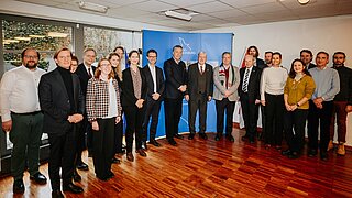 Group photo of all event participants in front of a blue press wall of the state of Brandenburg