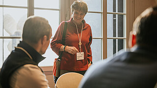 Friendly woman standing while talking to two seated men