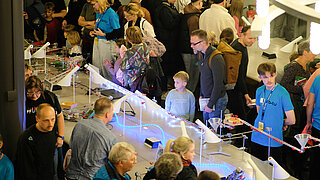 Participants in the Night of Creative Minds stand in front of an exhibition table.
