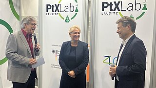 EN Harry Lehmann begrüßt gemeinsam mit Corinna Enders Bundesminister Robert Habeck, im Hintergrund die Plakate von PtX Lab Lausitz.