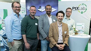 Fünf Mitarbeiter des PtX Lab Lausitz posieren vor ihrem Messestand