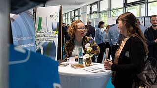 Eine Mitarbeiterin spricht mit einer Frau beim PtX Lab Lausitz Messestand