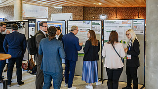 Eine gut besuchte Poster-Session des PtX Lab Lausitz auf der Nova-Konferenz 2025 in Köln. Fachbesucher und Teammitglieder stehen vor Stellwänden mit wissenschaftlichen Plakaten zu Themen wie E-Kerosin und nachhaltiger Chemie und tauschen sich intensiv aus.