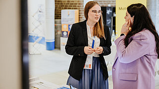 Dr. Sarah Bernhardt ist am Messestand des PtX Lab Lausitz im Gespräch mit einer Teilnehmerin
