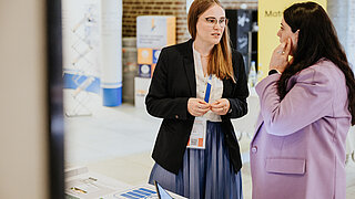 Dr. Sarah Bernhardt ist am Messestand des PtX Lab Lausitz im Gespräch mit einer Teilnehmerin