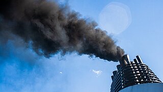Qualmender Schornstein vor blauem Himmel