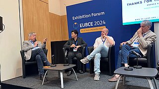 Vier Männer sitzen auf der Bühne und unterhalten sich