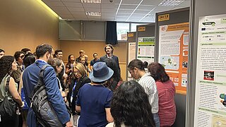 Nils Fuchs (PtX Lab Lausitz) stellt im Rahmen der EUBCE ein Poster vor. Er spricht dazu zu einer größeren Menschgruppe, die von hinten zu sehen ist.