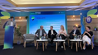 Panelrunde bei der EUSEW 2026, fünf Menschen sitzen rechts nebeneinander, links steht ein Mann an einem Stehpult