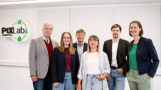 A group of three men and three women are standing in a row next to each other.