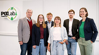 A group of three men and three women are standing in a row next to each other.