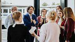 A group of people are standing in a circle, chatting.