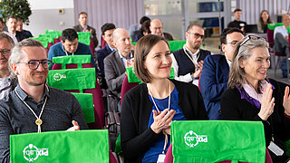 Mehrere Personen sitzen in einem Konferenzraum und klatschen.