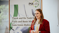 Weibliche Person steht vor einem Plakat in einem Raum.