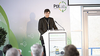 Eine männliche Person steht an einem Rednerpult. Im Hintergrund ist eine Pressewand mit dem Logo des PtX Lab Lausitz.