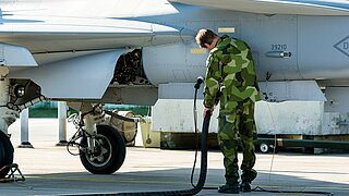 Ein Soldat betankt ein Militärflugzeug. / A soldier refuelling a military aircraft.