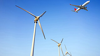 Ein Flugzeug überfliegt Windkraftanlagen.