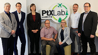Gruppenfoto des Teams des PtX Lab Lausitz, im Hintergrund ist das Logo zu sehen.
