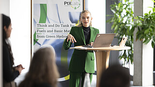 Eine Frau am Rednerpult. Dahinter ein Rollup des PtX Lab Lausitz.
