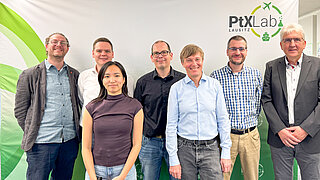 Eine Gruppe von Personen steht vor einer Pressewand des PtX Lab Lausitz.
