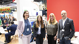 Four people standing at an exhibition booth.